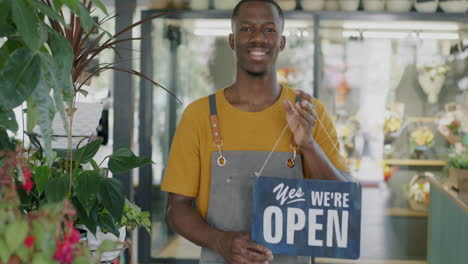 smiling florist employee holding open sign