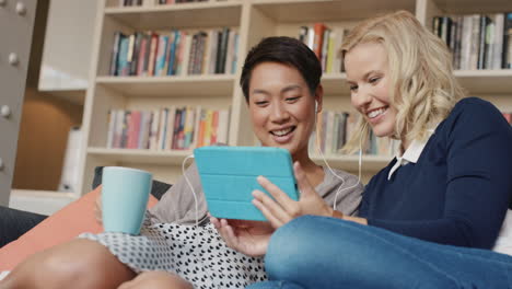 friends at home hanging out on sofa sharing using digital tablet reading social media