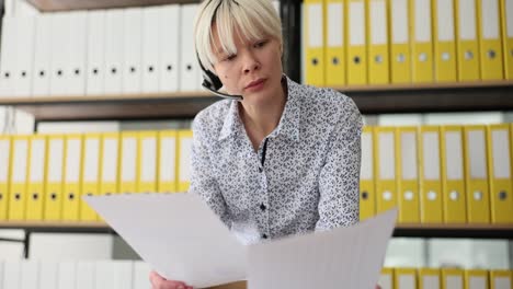 woman with headset reviewing documents in an office