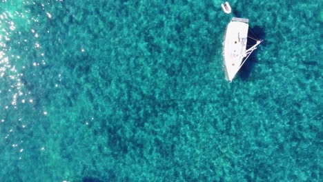 Flying-over-little-boats-and-people-swiming-in-clear-watter,-up-to-the-port-of-Saint-Honorat-island-part-of-the-Iles-de-Lérins,-next-to-Cannes-in-south-of-France-in-mediterranean-sea