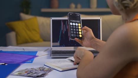 la mujer calculando por teléfono. está tomando notas.