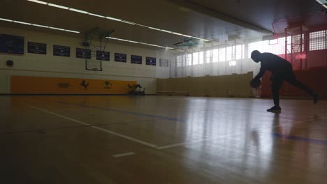 male runningafter ball while playing alone on basketball court in 4k