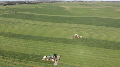 Rotación-Panorámica-Aérea-Alrededor-De-Dos-Tractores-Que-Conducen-En-Cualquier-Dirección-En-El-Paddock