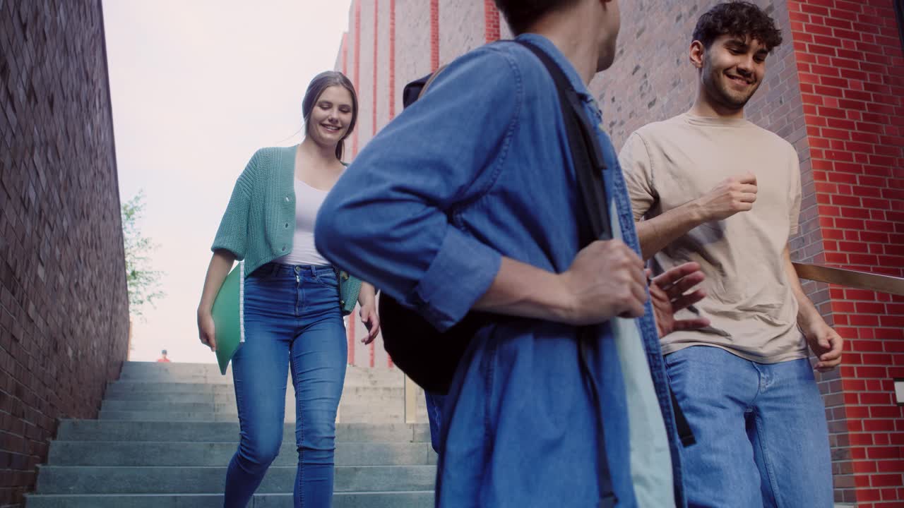 tres estudiantes caucásicos caminando por las escaleras en el campus universitario