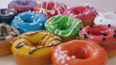 close-up you can see how delicious sweet donuts are laid out on the table, decorated with multi-colored icing and white-dark chocolate with colored sprinkles. sweets close-up. obesity concept