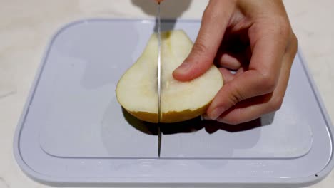 hands slicing a pear on a cutting board