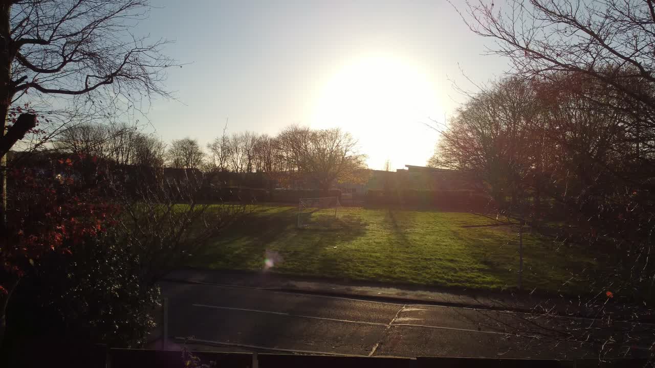 Rising from back garden to long autumn shadows across British neighbourhood school landscape aerial view