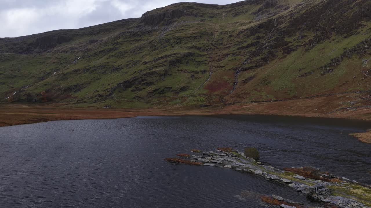 Aerial drone footage of Llyn Cwmorthin and the Moelwyn Mawr range in Eryri National Park, capturing serene lakeside scenery, dramatic Welsh mountains, and the region’s slate-mining heritage