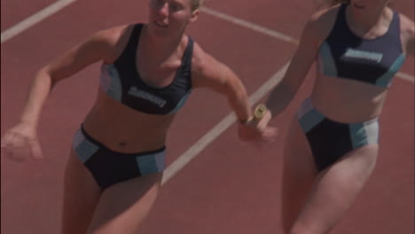 a female runner passes the baton in a relay race