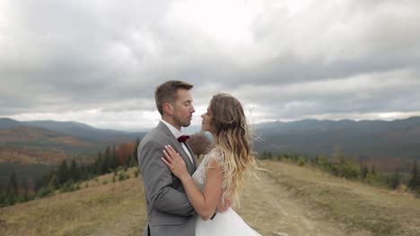 Lovely-young-newlyweds-bride-groom-walking-on-mountain-slope,-making-a-kiss,-wedding-couple-family