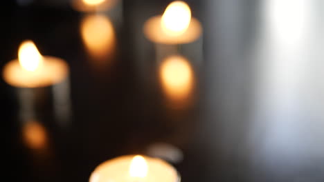 a blurry background shot with tealight candles burning and flames dancing in heavy bokeh