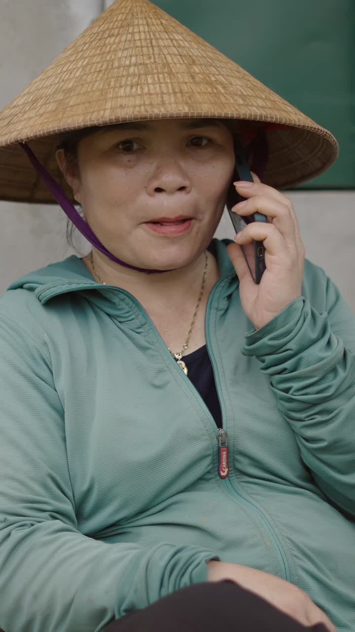 Woman in Asian conical hat talking on cell phone