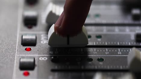 person's index finger slide up the fader to the maximum volume of mixing console