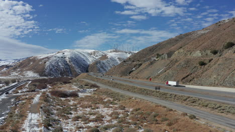 Vuelo-Lento-Por-La-Carretera-De-Montaña-Nevada-En-California-Con-Camiones-Y-Autos