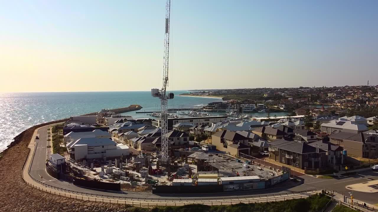 New coastal housing development with crane in Mindarie, Australia at sunset by the ocean