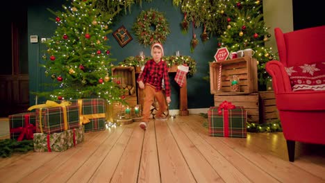 Boy-wearing-a-Santa-hat-is-sliding-on-the-floor-out-of-happiness-in-Christmas-decorated-living-room