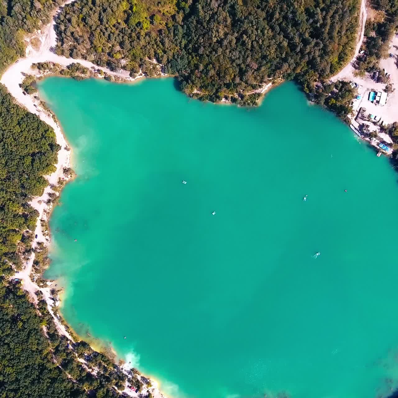 Breathtaking scenery over the turquoise lake in the middle of the thick woods. Deep waters surrounded by the beautiful scenery. Birds eye view