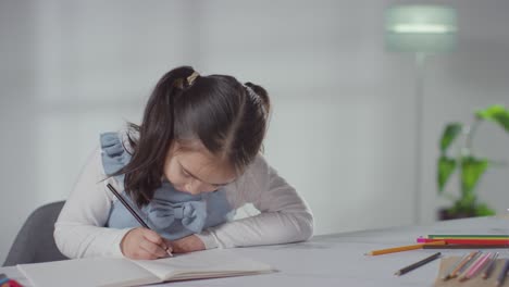 Young-Girl-On-ASD-Spectrum-At-Table-At-Home-Concentrating-On-Writing-In-School-Book-2