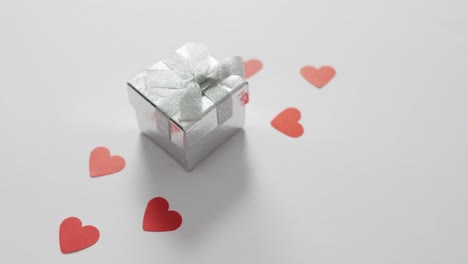 paper hearts and gift on pink background at valentine's day