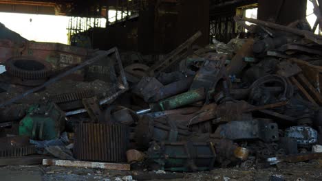 exterior view of abandoned soviet heavy metallurgy melting factory liepajas metalurgs territory, rust-covered metal scrap piles, sunny day, medium shot