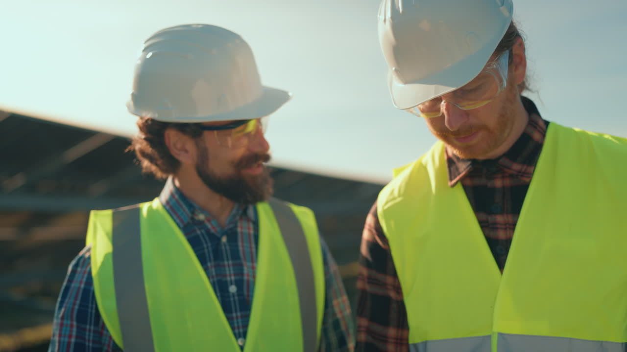 Construction Workers Discussing Plans at Solar Panel Installation Site
