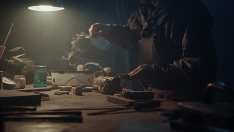 a bombmaker assembles a bomb in his workshop at night
