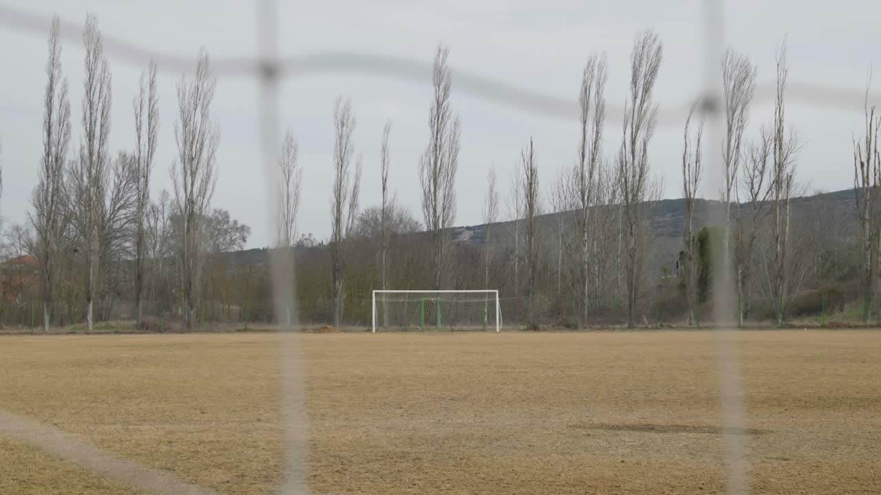 Empty local amateur football field in autumn shot behind opponents net slow motion bokeh