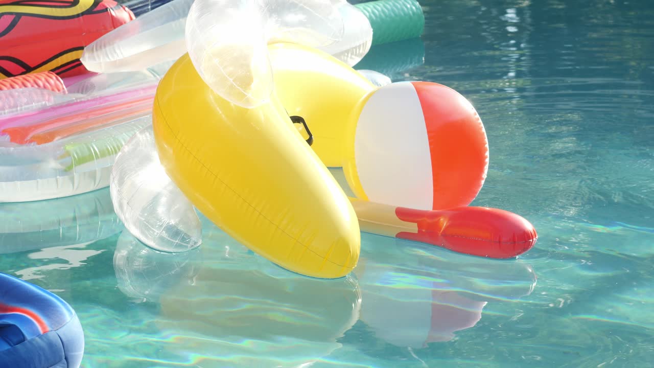 An assorted collection of pool toys floats in the water, the prominent one being a banana