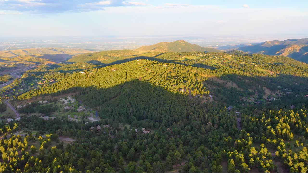 High-altitude cinematic drone view of Colorado Rockies at golden hour, warm glow over rocky cliffs, alpine meadows, and panoramic vistas, stunning 4K aerial summer mountain footage with vivid details