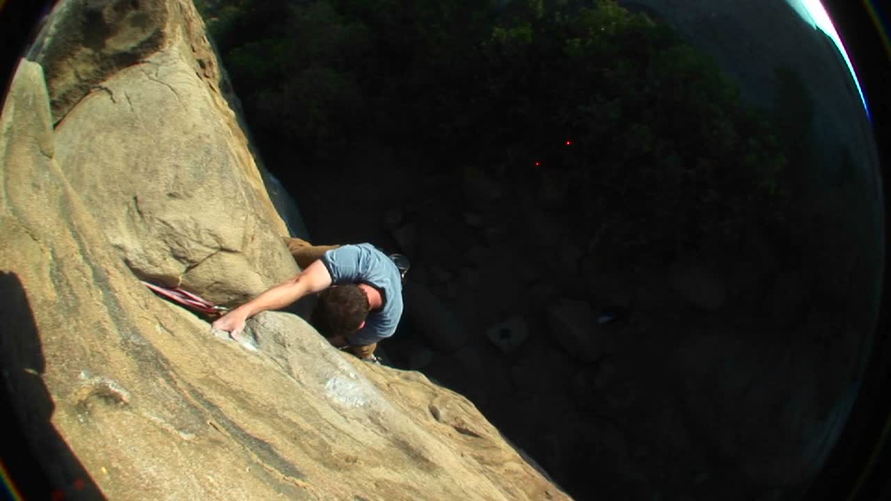 Fisheye Shot Of A Rock Climber Climbing Up Cliff Face