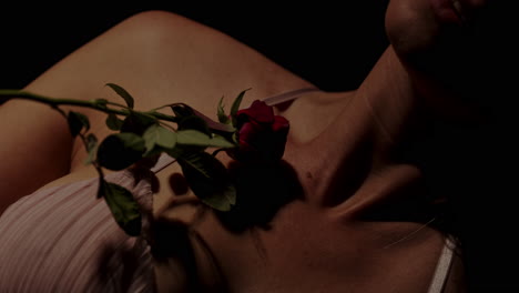 an attractive woman in enticing lingerie sensually strokes a red rose on her beautiful body in slow motion