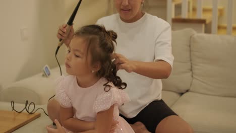 madre embarazada peinando el cabello de su hija en casa