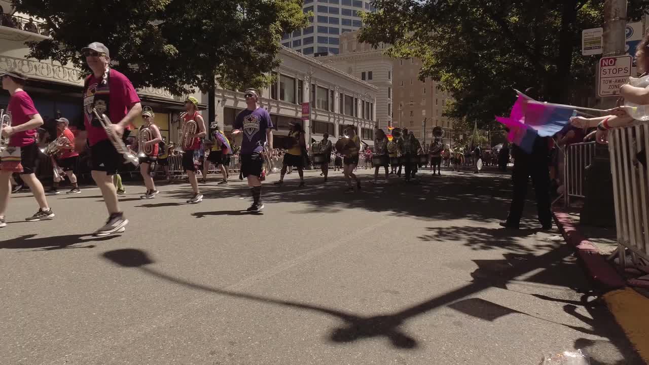Seattle Sounders employees and band members participating in the Seattle LGBTQ parade, marching band, waving rainbow flags