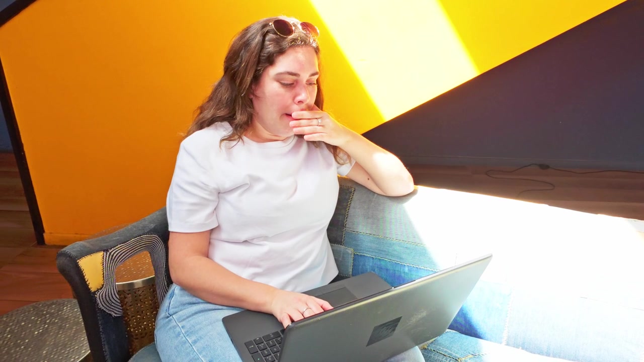 Kvinne jobber på bærbar PC i en moderne coworking-lobby.