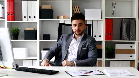 hombre de negocios sentado en la mesa en la oficina blanca y lanzando las manos detrás de la cabeza balanceándose en la silla de oficina