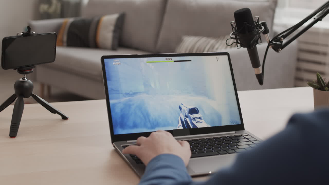 Gaming setup with laptop, microphone, and smartphone