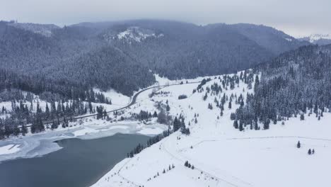 Autos-Fahren-Auf-Windiger-Bergtalstraße-In-Gefrorener-Winterschneelandschaft,-Drohnenkranschuss