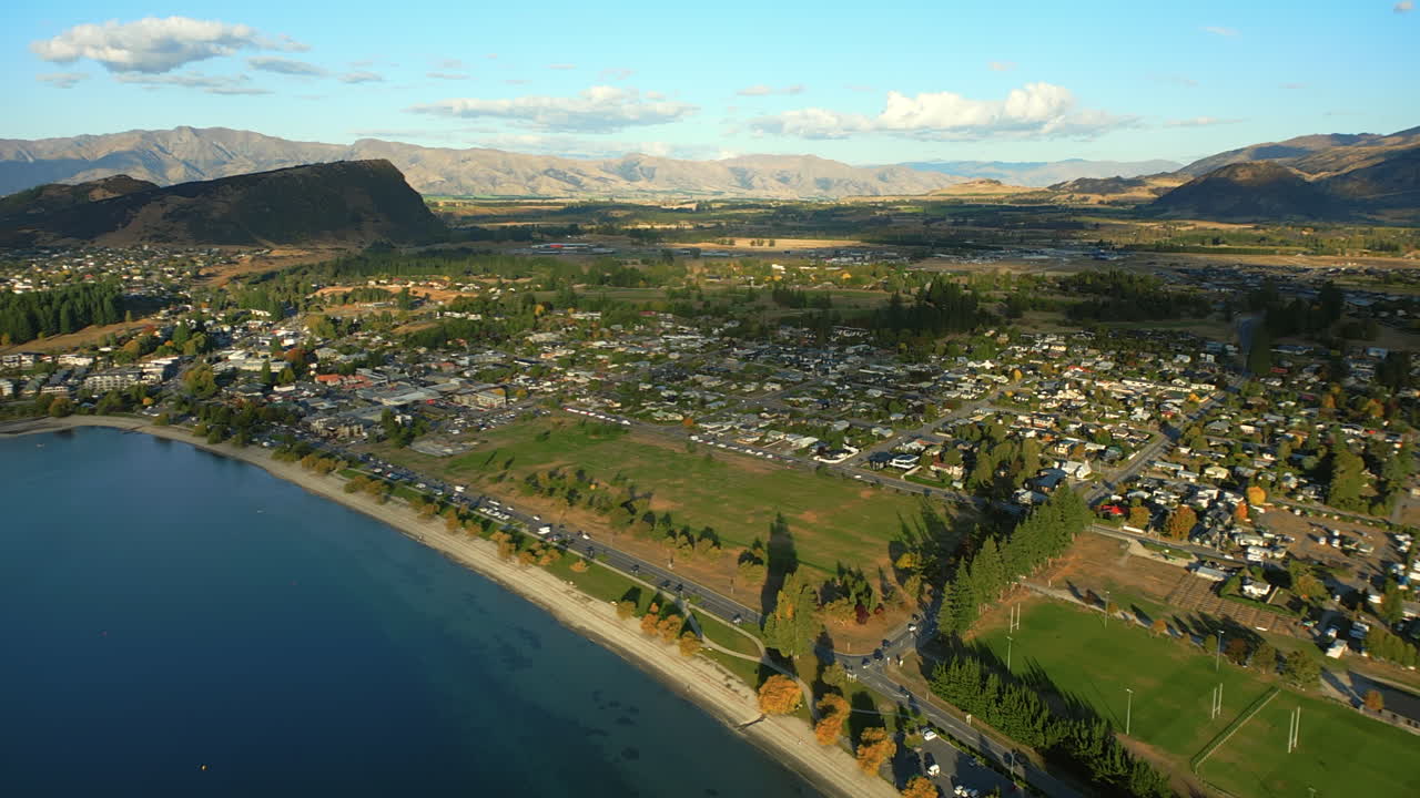 Wānaka resort town and main beach at sunset on Lake Wānaka, South Island, New Zealand - pullback aerial