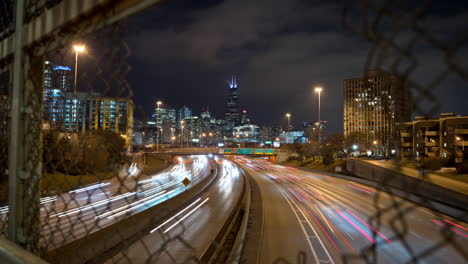 one second long exposure time lapse push in revealing traffic through a hole in a fence over the kennedy expressway in chicago