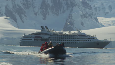 a zodiac with passengers leaves the ship to explore icebergs in antarctica