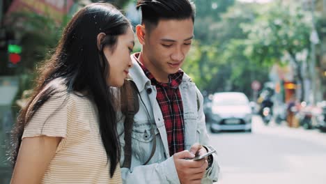 Vista-Portátil-De-Una-Pareja-Vietnamita-Mirando-El-Teléfono-Móvil