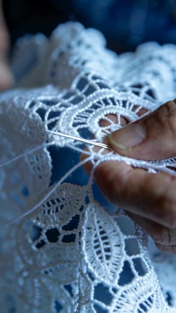 Vertical video: Inserting needle, senior hands pulling thread through lace at table, joining motifs