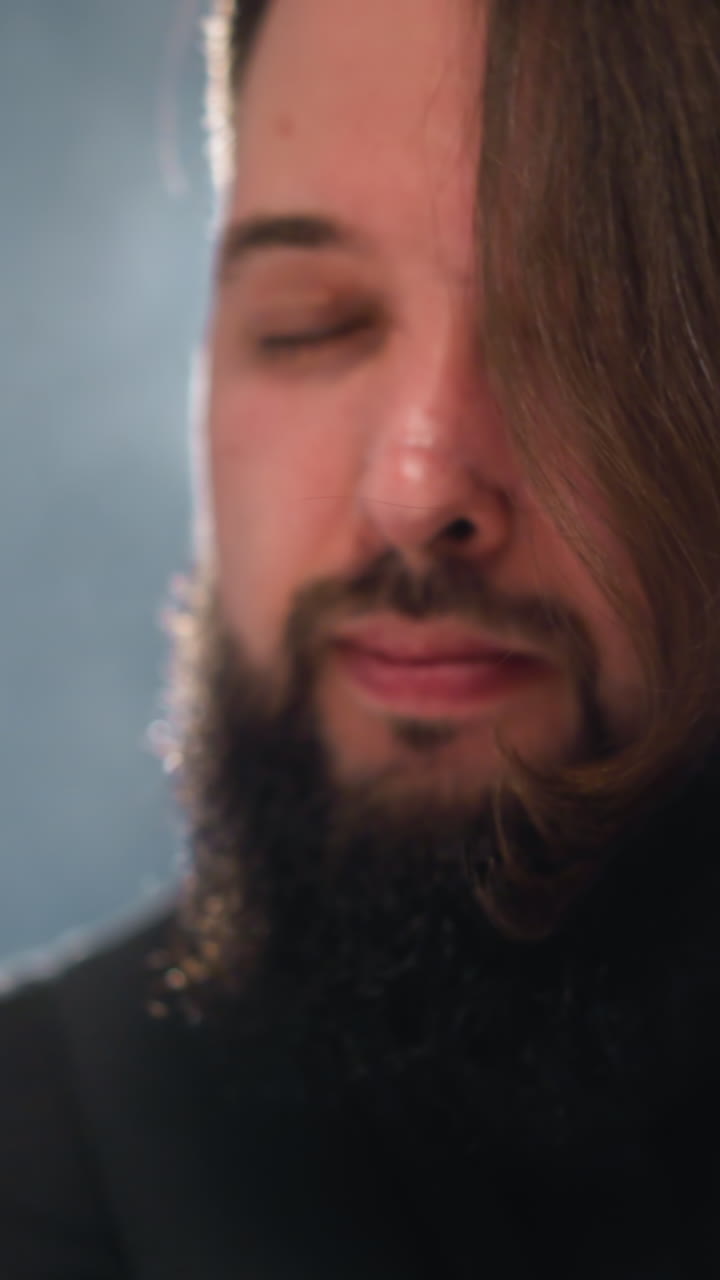 intenso primer plano de un hombre barbudo con una camisa negra, emocionalmente atractivo, con un fondo borroso