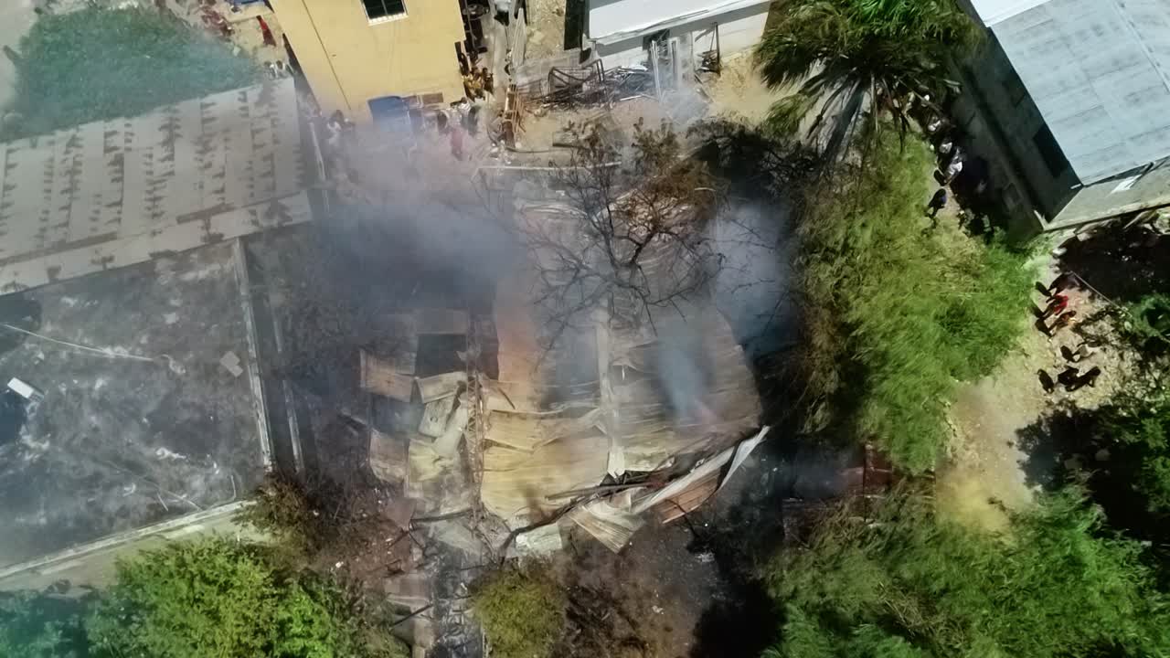 vista aérea alrededor de las ruinas de una casa humeante, en una ciudad soleada - dando vueltas, tiro de drones