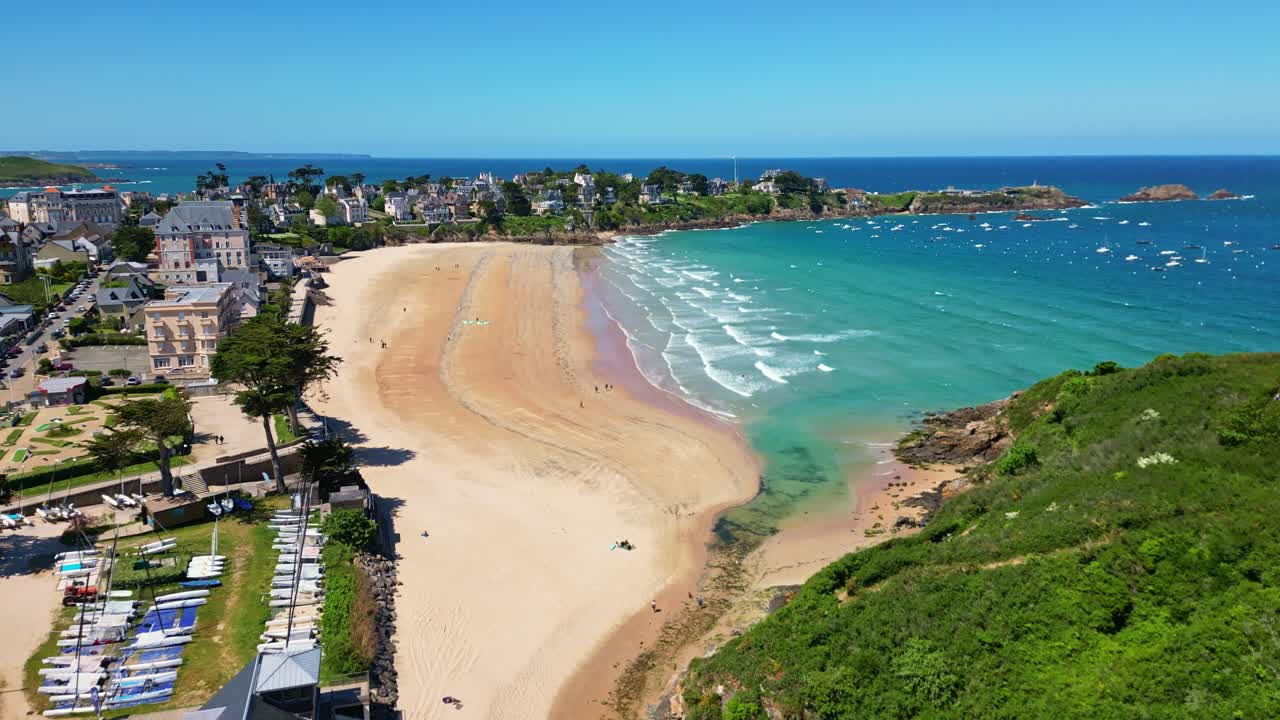 Saint-Lunaire beach, France, golden sand, turquoise sea, coastal town. Aerial forward tilt-up reveal