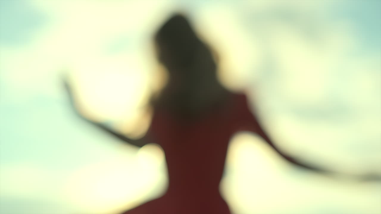 A young woman enjoys the sunlight as she smiles softly, surrounded by open skies and natural light