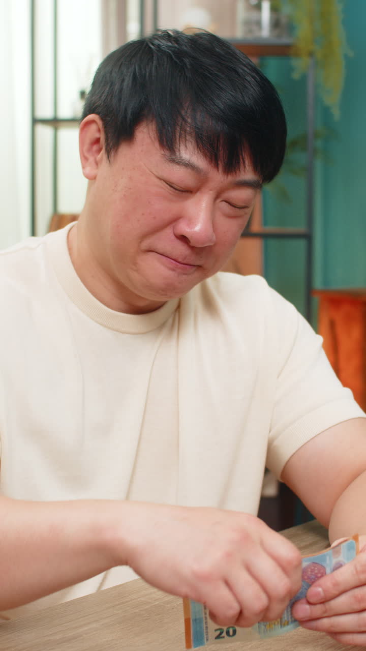 Asian man counting happily money euro cash pleased with earned income celebrates big financial gain