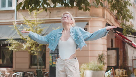 blonde woman in glasses taking a deep breath of fresh air relaxing meditating on urban city street