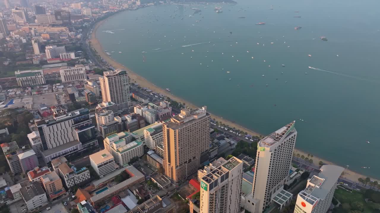Il paesaggio urbano di Pattaya risplende sopra un mare tranquillo all'alba, Thailandia