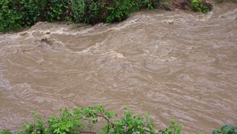 río sucio con agua fangosa después de fuertes lluvias que causan inundaciones y fuertes corrientes